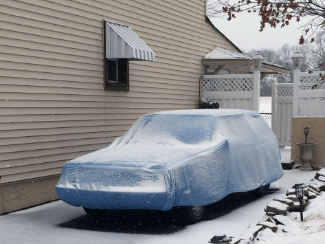 An original K car wagon sits under snow and a car cover this morning